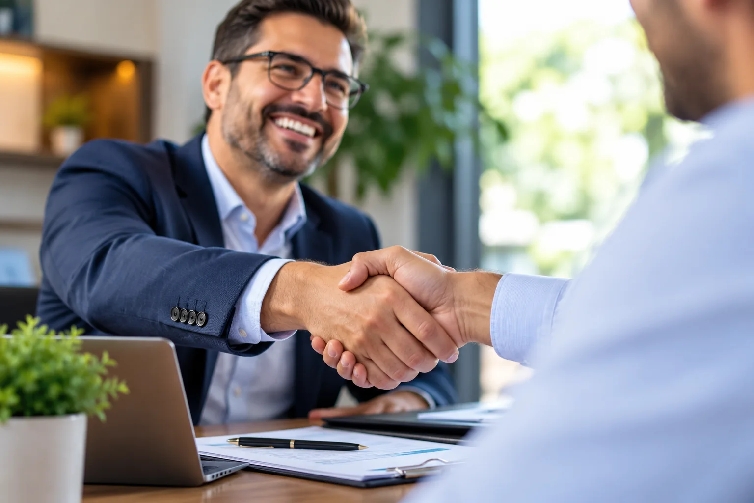 Asesor y cliente estrechándose la mano en una reunión profesional